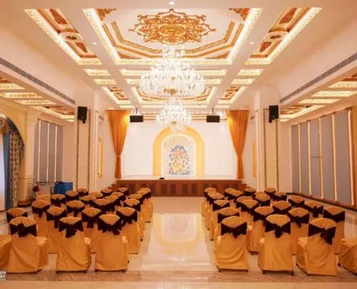 Dwaraka Palace: an elegant hall with chandeliers, a golden ceiling and a stage with a peacock mural